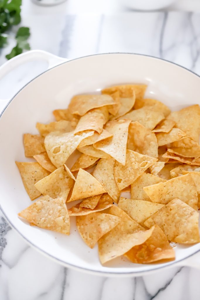 Tortilla chips on a white pan ontop of a marble backdrop