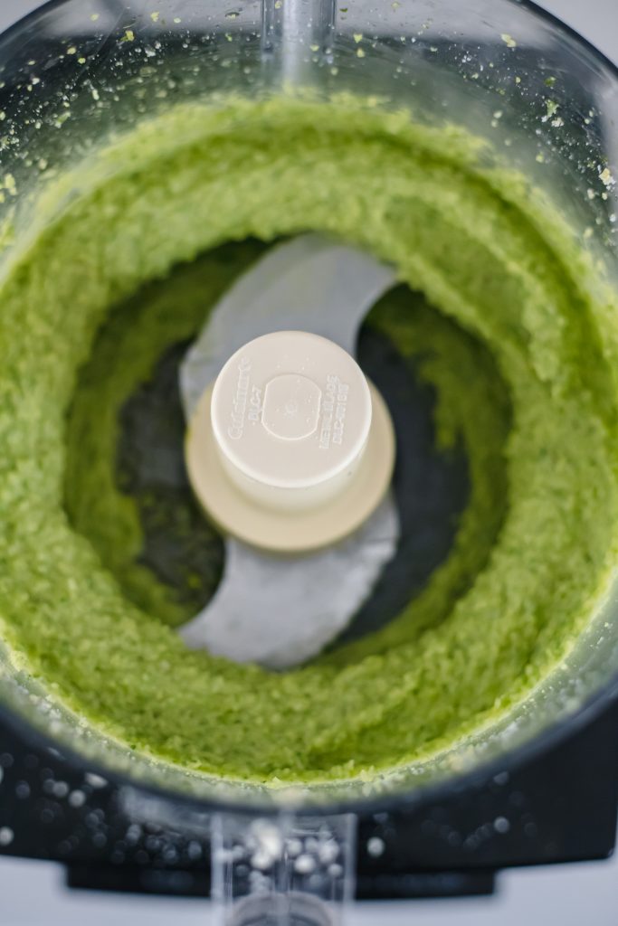 How to make basil pesto: vibrant green pesto in the bowl of a food processor