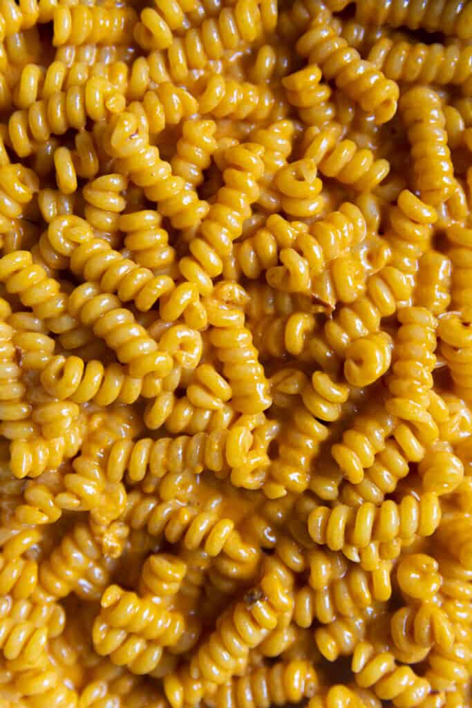 Upclose macro shot of corkscrew pasta in a vibrant orange sauce. Looks cheesy.