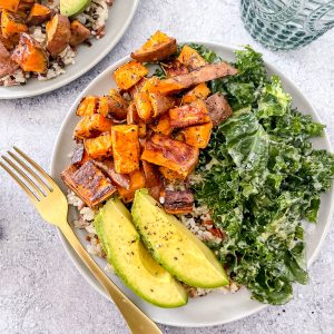 A bowl with brown rice, topped with roasted sweet potatoes, massaged kale, and vibrant avocado.