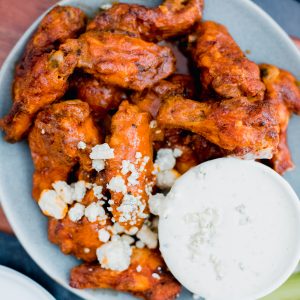 Bowl with buffalo wings and a small container of white dressing.