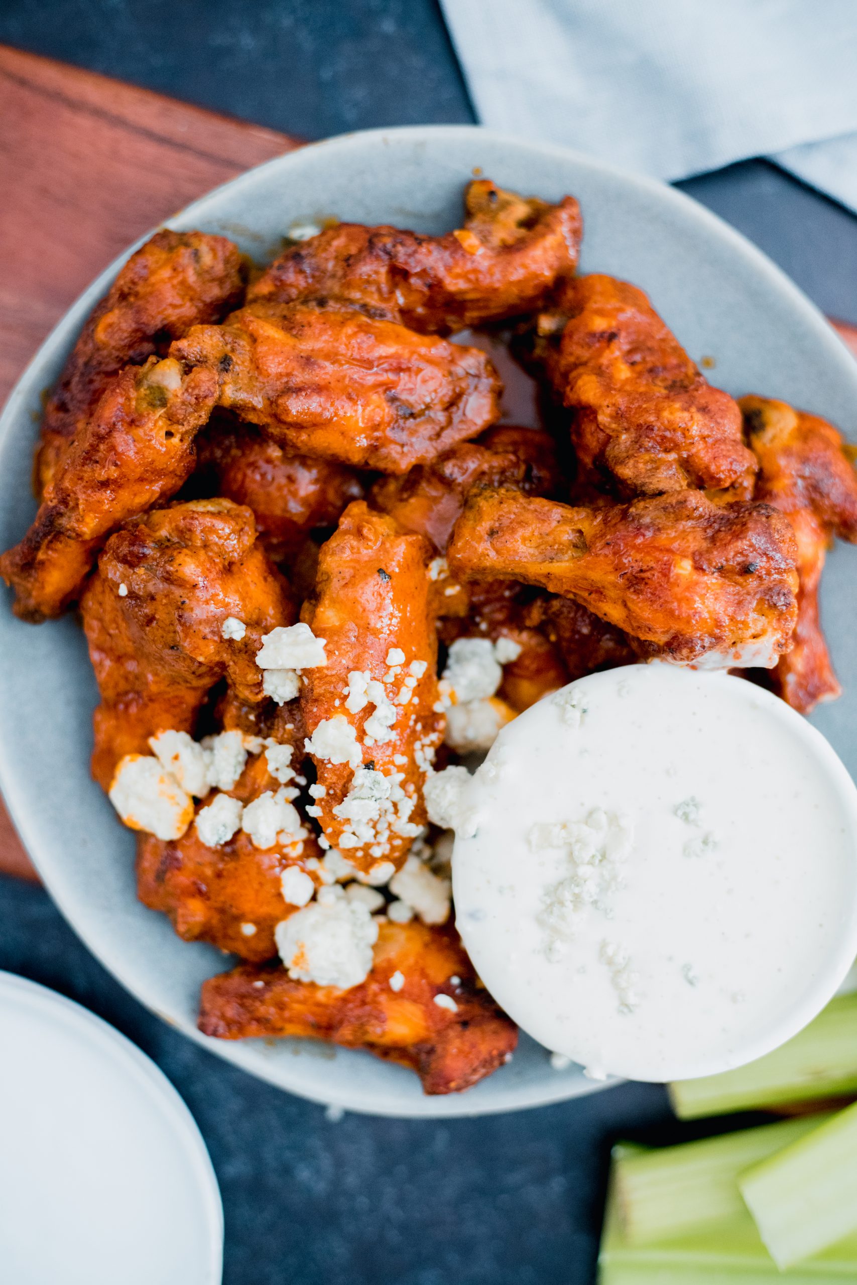 Bowl with buffalo wings and a small container of white dressing.