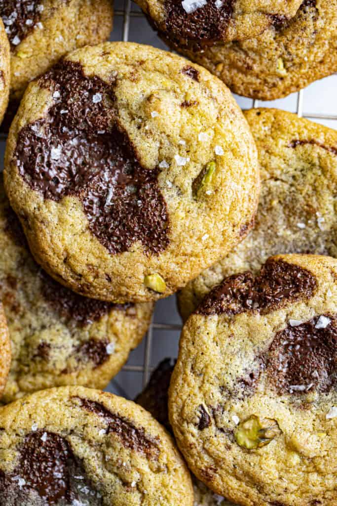Overhead zoomed in shot of chocolate chunk cookies with pistachios in them with flaky salt.