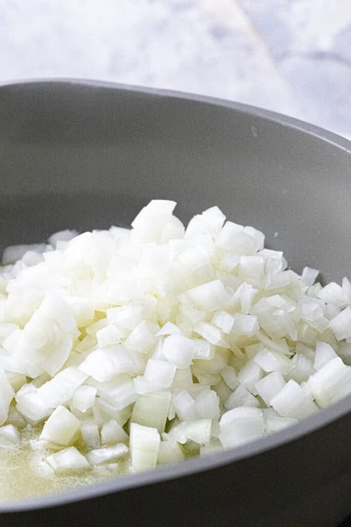 Diced white onion in a pan with melted butter.