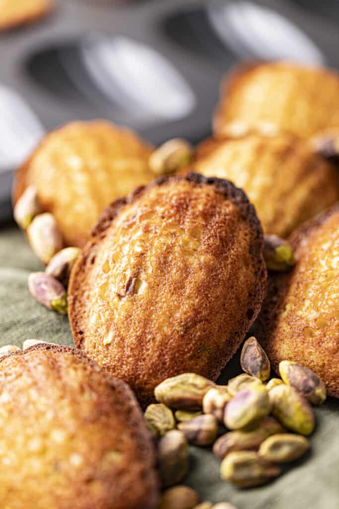 Pistachio Madeleines laying on a green linen napkin with pistachios