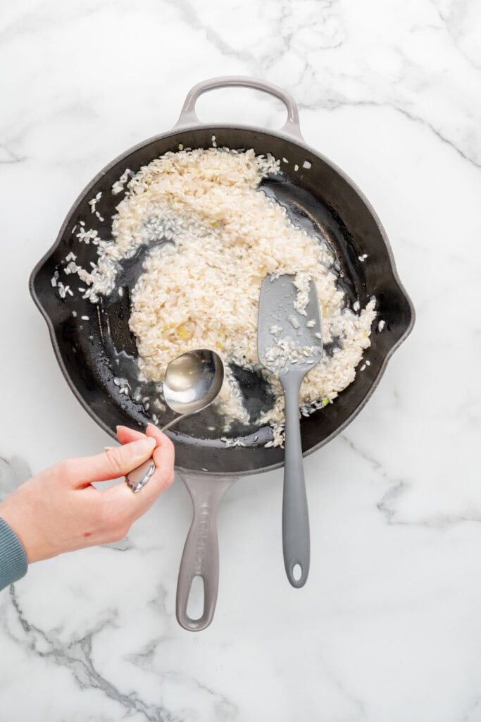 Cooking risotto al limone by slowing adding broth.