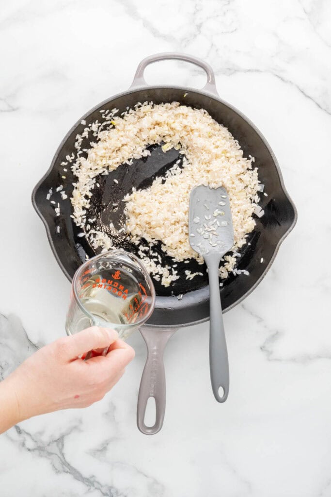 Deglazing a pan with white wine to make risotto al limone.