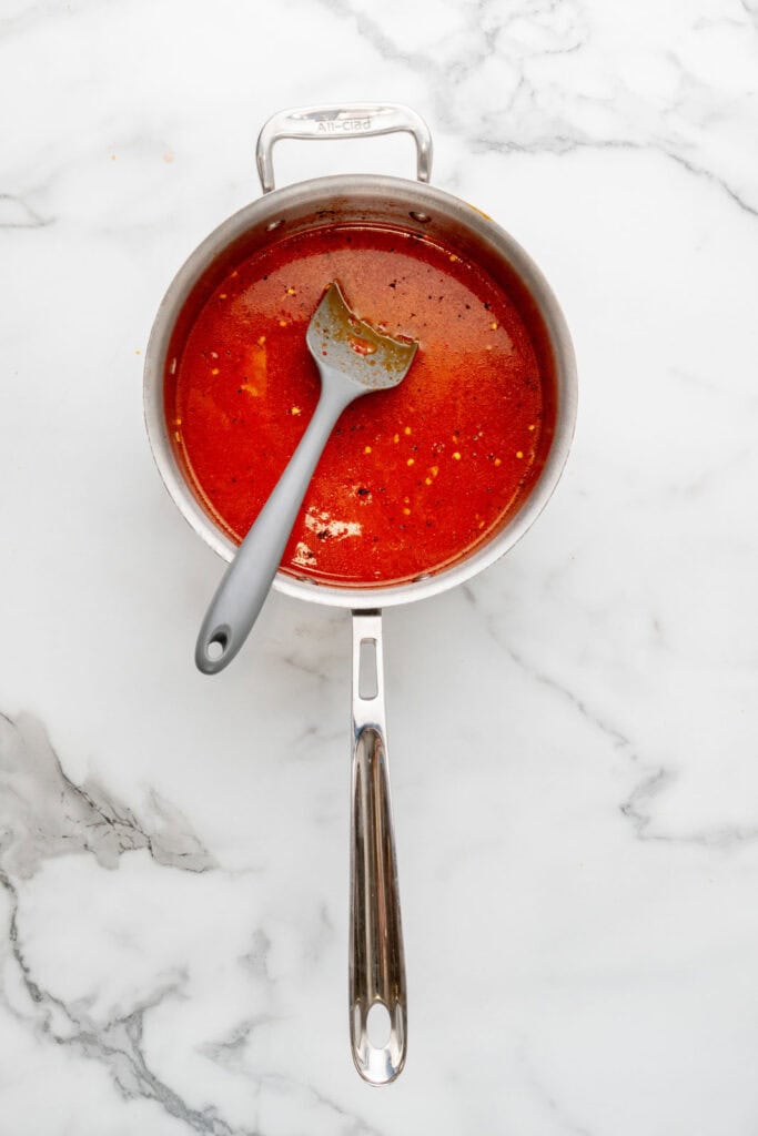 Simmering stock and crushed tomatoes to make tomato pastina.