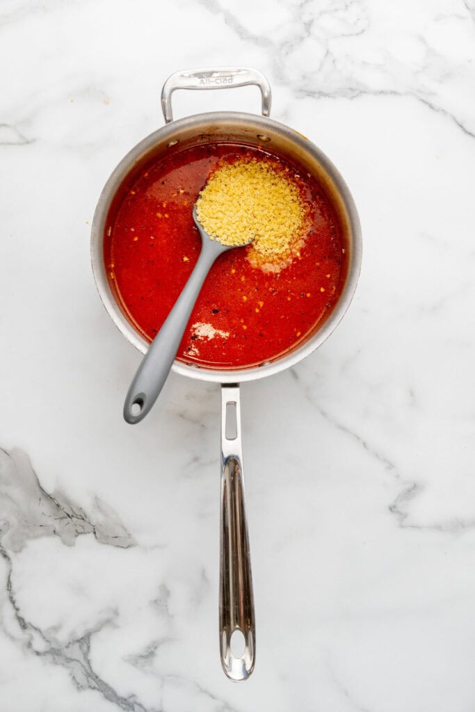 Adding pastina to tomatoes and broth.