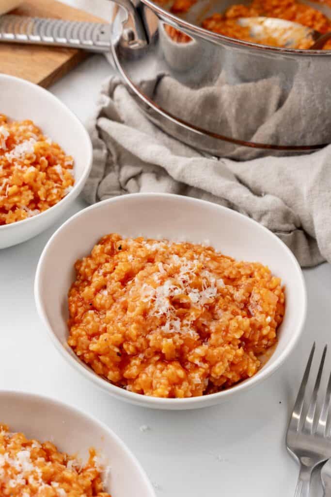 A bowl of tomato pastina with grated cheese on top.
