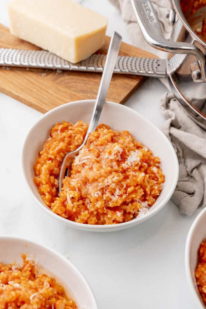 A bowl of tomato pastina with grated cheese on top.