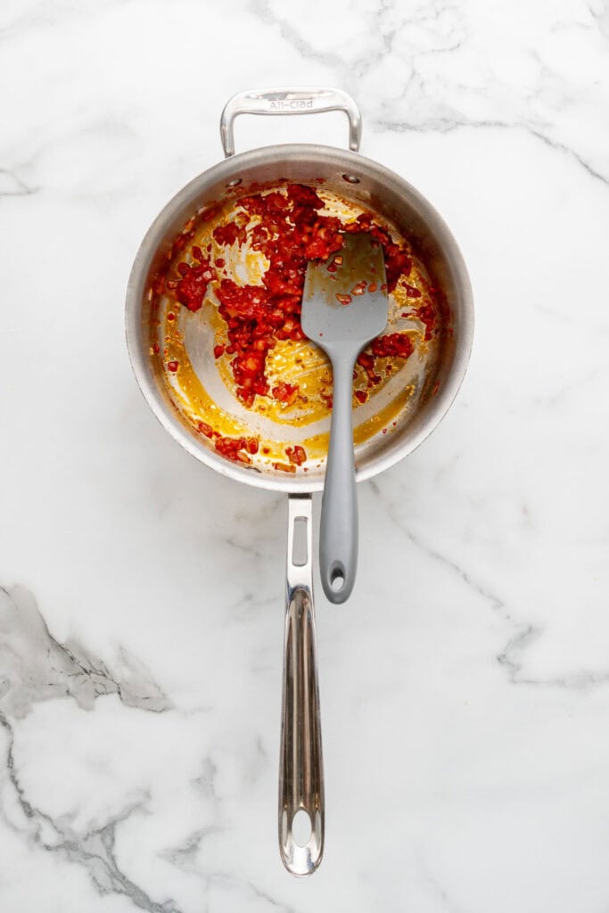 Starting to cook tomato pastina by cooking tomato paste and shallots with garlic.