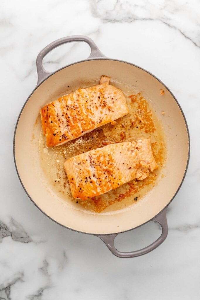 Searing salmon in a pan.