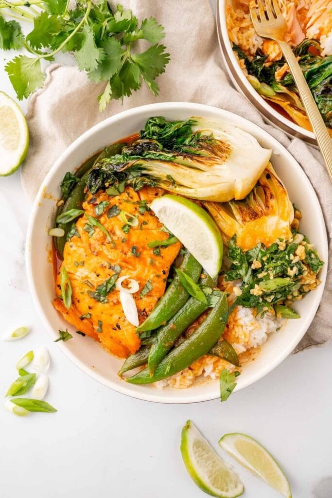 Salmon with coconut curry and rice in a bowl with bok choy and snap peas.