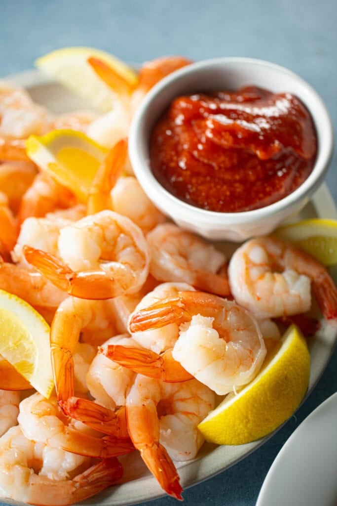 Poached shrimp with cocktail sauce and lemon slices.