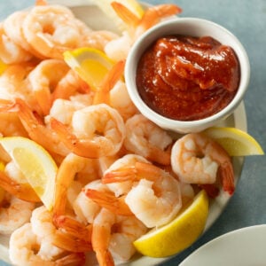 Poached shrimp with cocktail sauce and lemon slices, zoomed in.