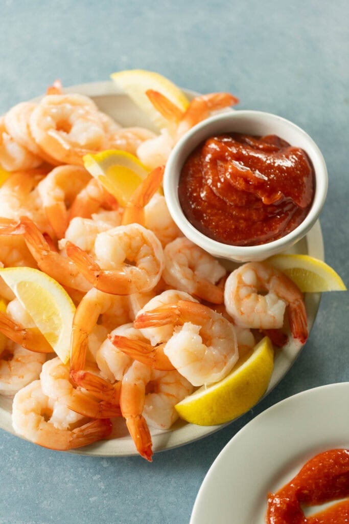 Poached shrimp with cocktail sauce and lemon slices.