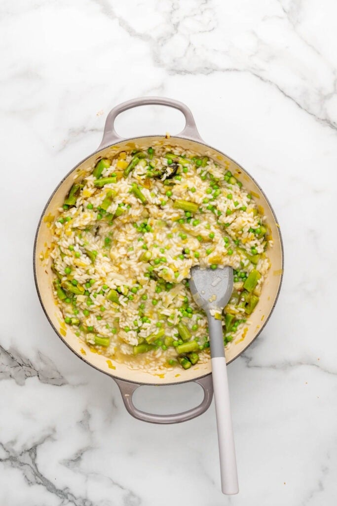 Spring risotto with asparagus and peas in a pan.