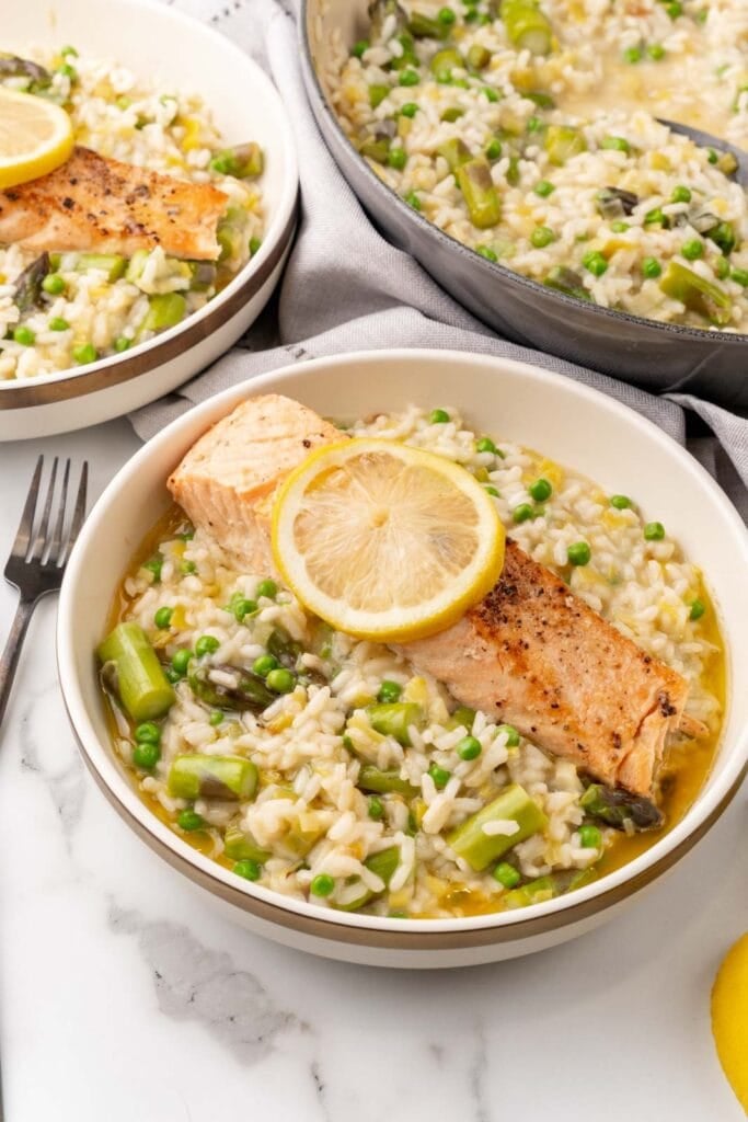 Risotto with salmon in a bowl with asparagus and peas.
