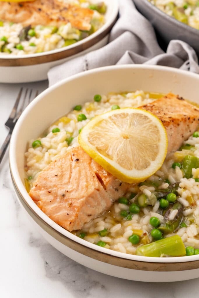 Risotto with salmon in a bowl with asparagus and peas.