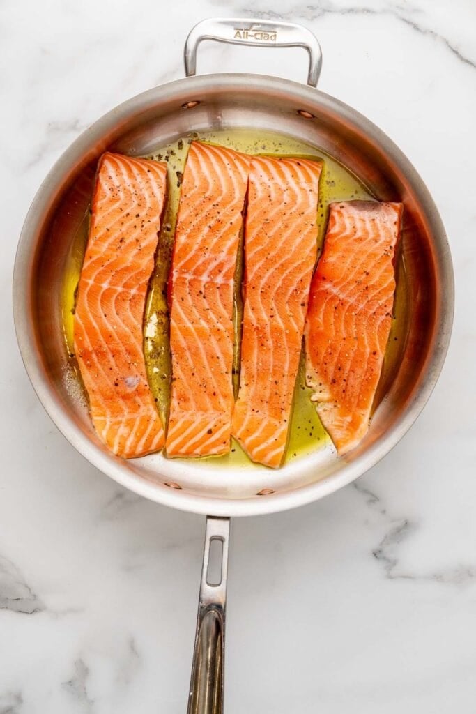 Searing salmon in a pan.