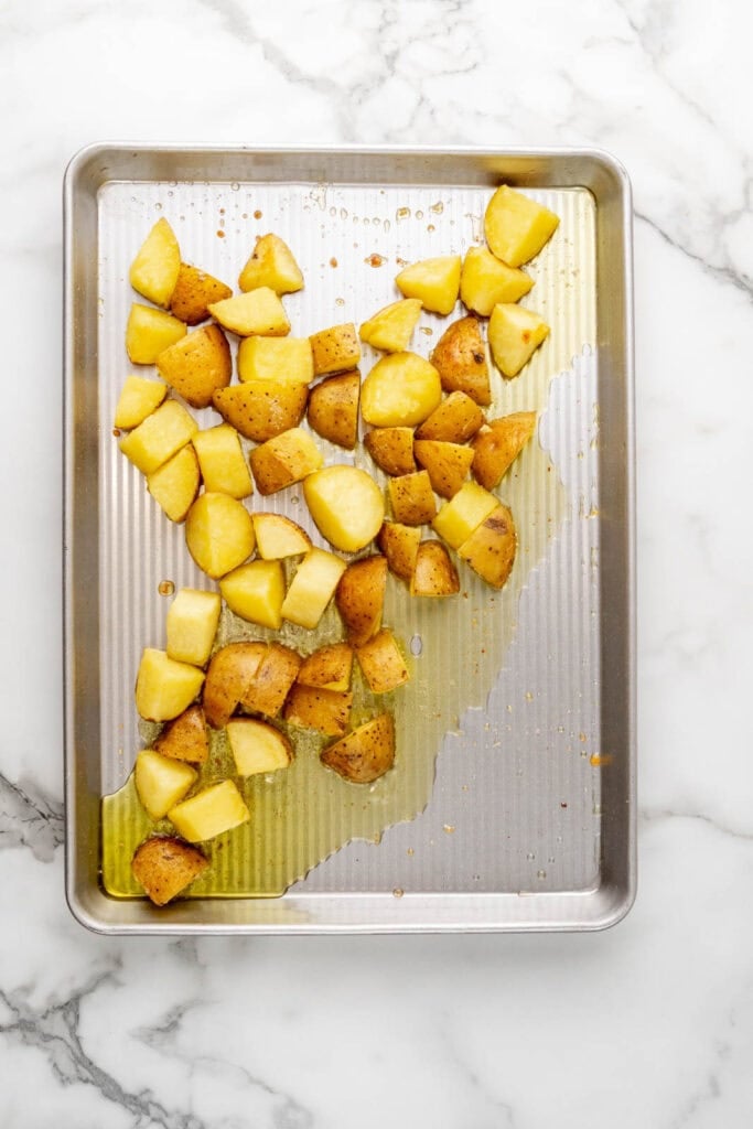 Potatoes and olive oil on a sheet pan.