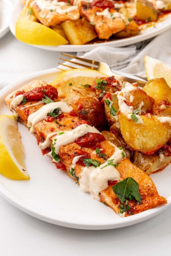Salmon and potatoes with bravas sauce and aioli on a plate.