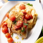 Seared chicken breasts with cherry tomato sauce and polenta on a plate.
