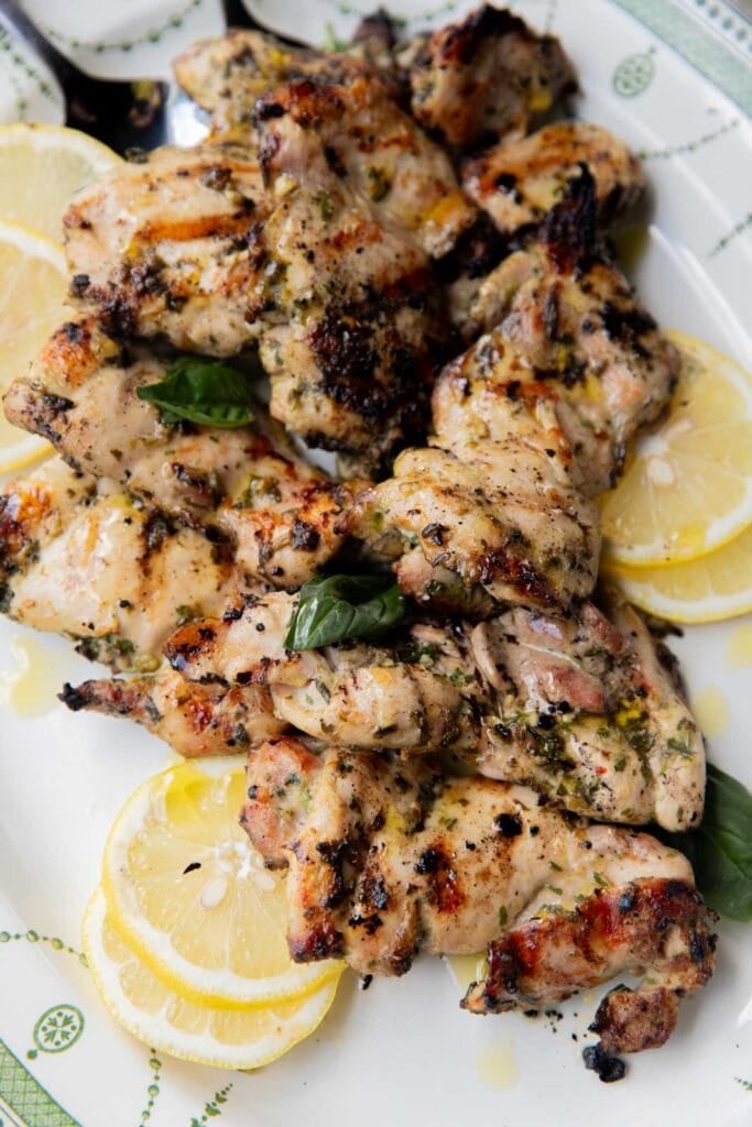 Grilled chicken thighs with chimichurri sauce and lemons.