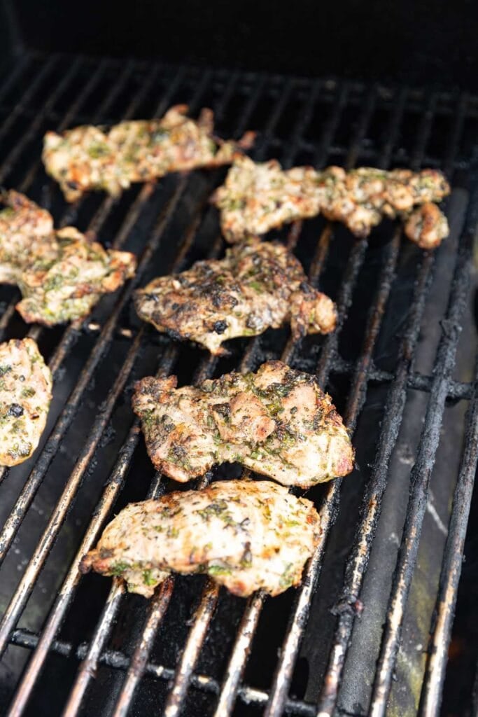Grilling chicken thighs on a grill.