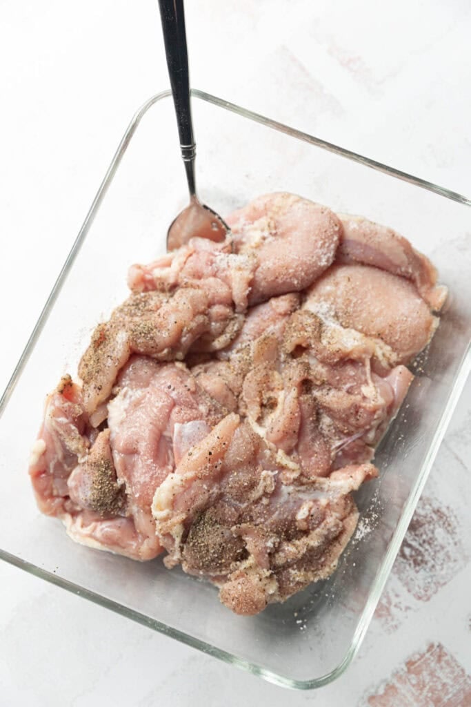 Chicken thighs seasoned with salt and pepper.