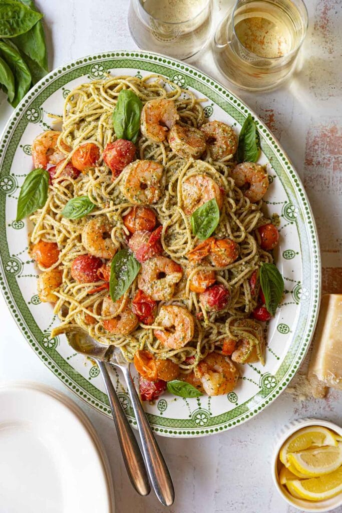 Pesto shrimp spaghetti with cherry tomatoes on a serving platter.