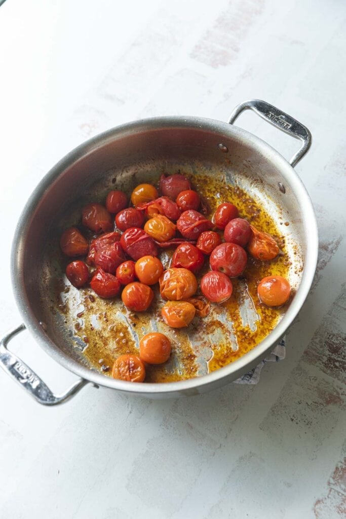 Bursting cherry tomatoes in a pan.
