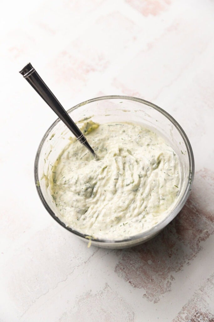 A greek yogurt based sauce with cucumber and dill in a small bowl.