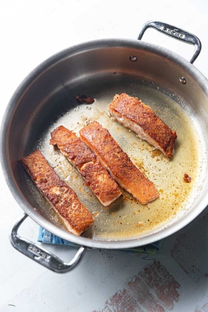 Searing salmon in a pan.